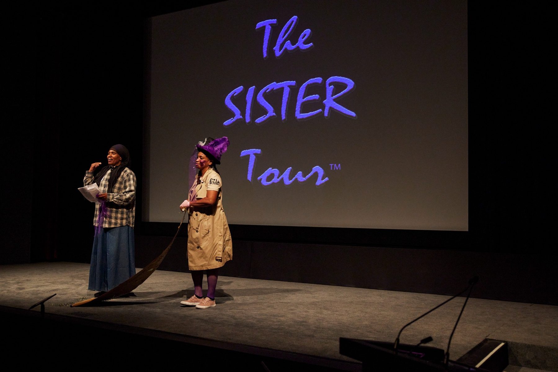The Sister Tour performers on stage beneath a purple Sister Tour projection